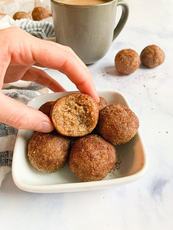 vegan cinnamon donut holes in a small bowl with coffee in the background 