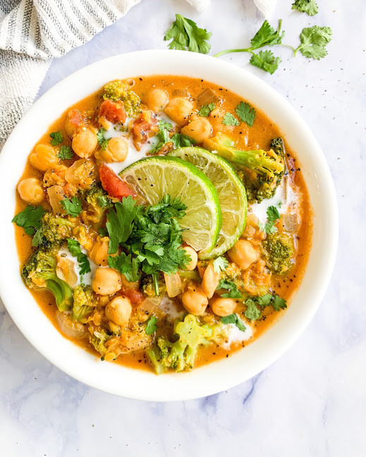 vegan coconut chickpea curry soup in a white bowl next to a napkin and cilantro 