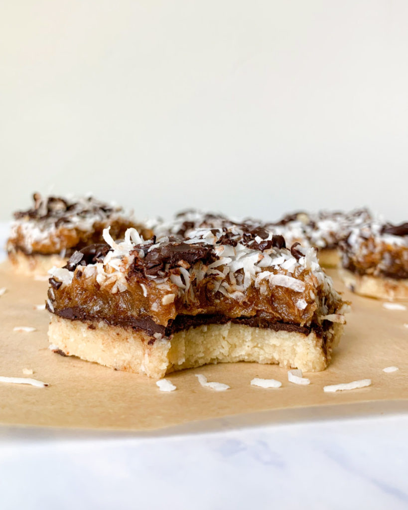 a vertical image of a healthier vegan no bake samoa bar on a white counter top with more bars in the background  