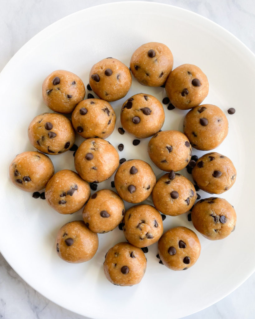 healthy vegan peanut butter balls with chocolate chips on a white plate on a white counter top 