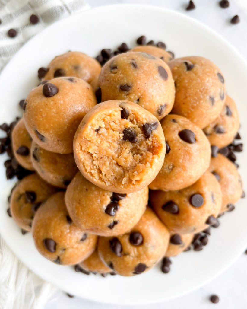 vegan peanut butter cookie dough balls  with chocolate chips on a white plate on a white counter top 