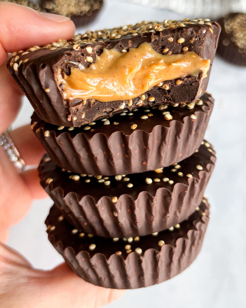 a hand holding a stack of vegan crispy quinoa peanut butter cups