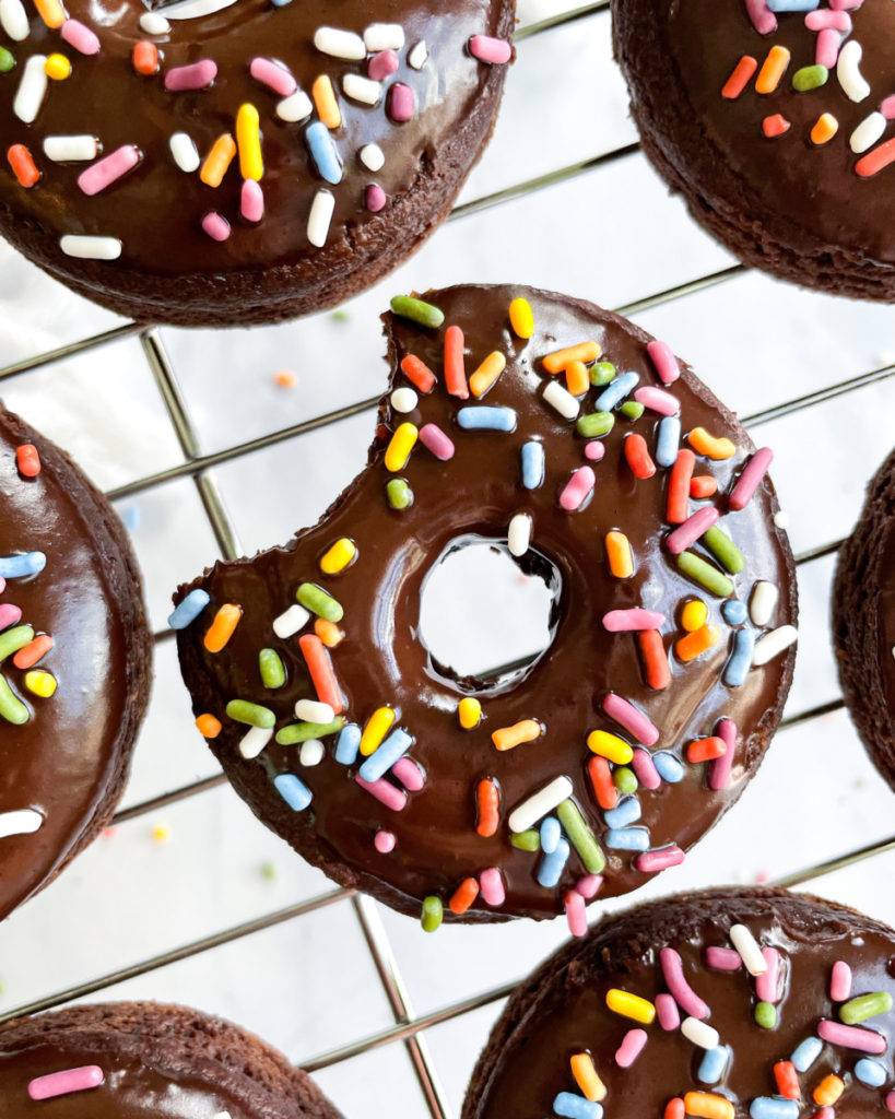 vegan oil-free chocolate baked donuts on a cooling rack on a white counter top 